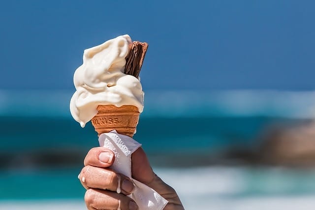 Person holding ice cream at a beach seaside